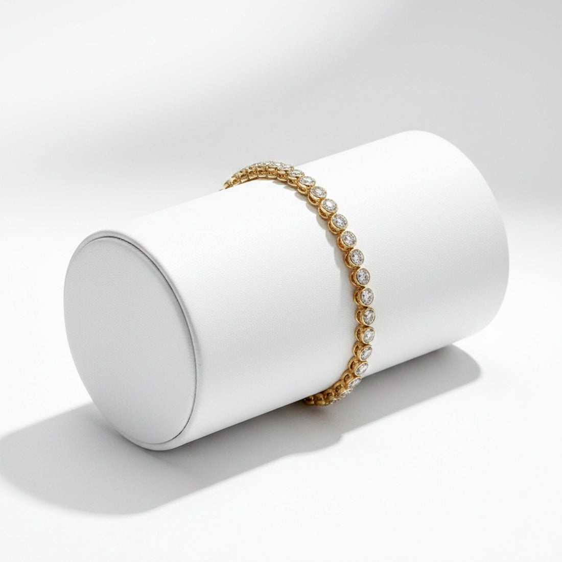 Gold and pearl bracelet on a white cylindrical stand against a light gray background