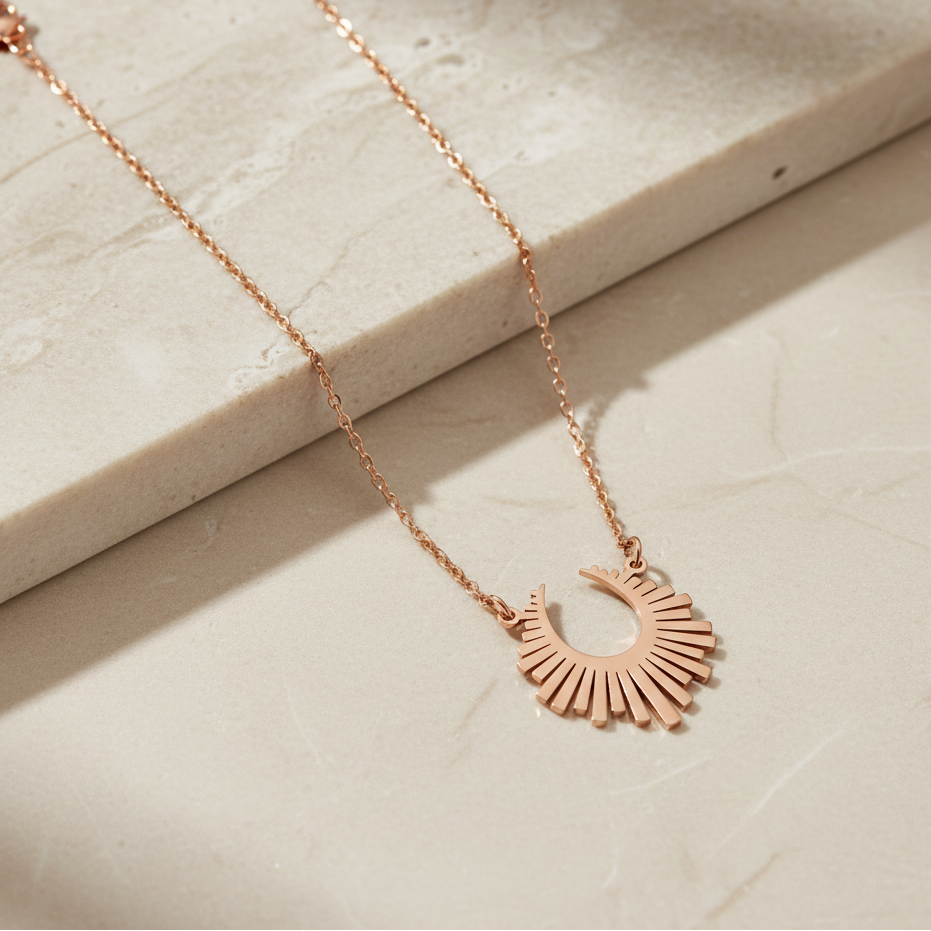 Rose gold necklace with a unique pendant on a light stone surface